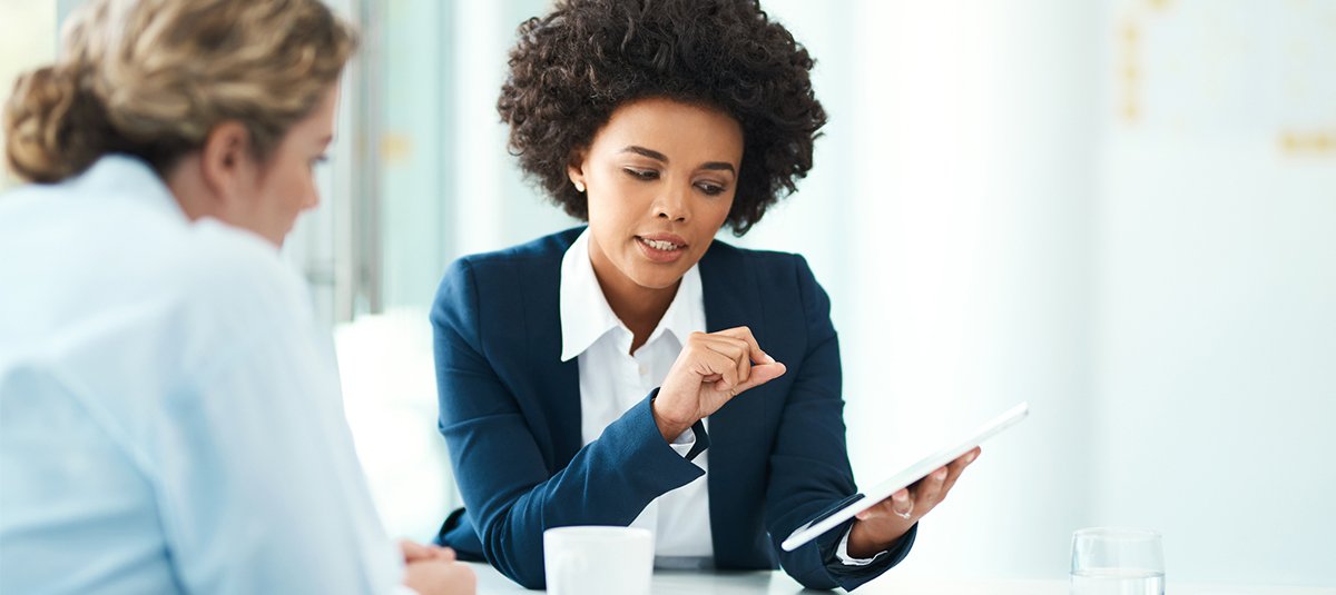 Woman explaining something on tab to another woman