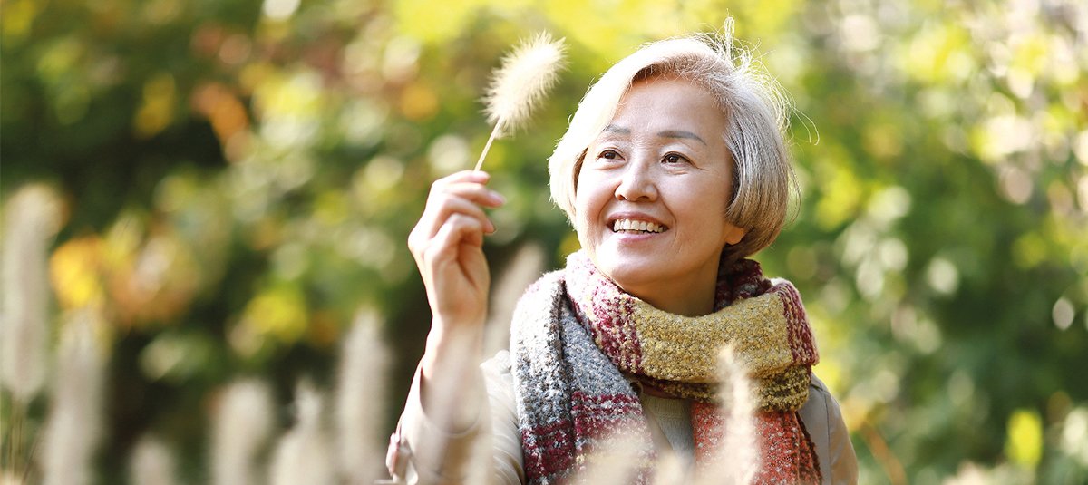 Woman smiling while looking at leaf in hand